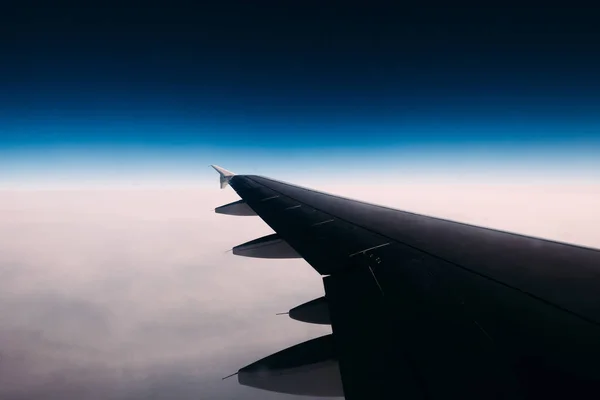 Uitzicht vanuit vliegtuig raam op wolken onder en duidelijke donkerblauw — Stockfoto