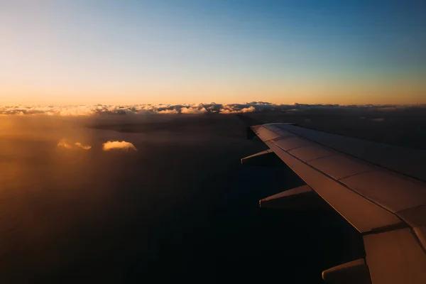 Asa de avião em luzes de pôr do sol com nuvens distantes e céu azul — Fotografia de Stock