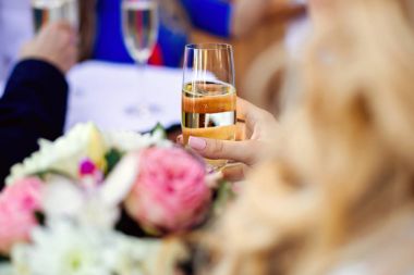 Kadın el cam şampanya ile resmi törenle üzerinde tutarak