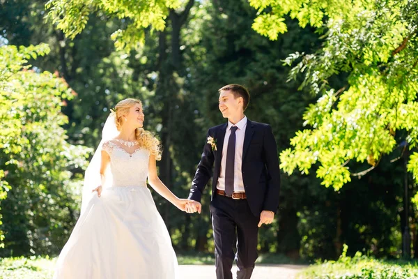 Ευτυχισμένος γάμος ζευγάρι περπάτημα στο πάρκο. Νεόνυμφοι περπάτημα, έχουν κ — Φωτογραφία Αρχείου
