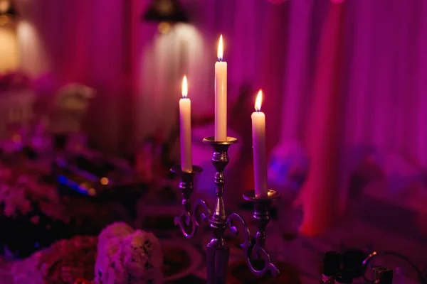 Three candles creating a cozy atmosphere on a wedding party on b