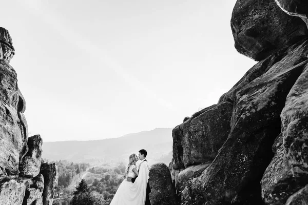 Casal encantador suavemente abraçando nas rochas nas montanhas . — Fotografia de Stock