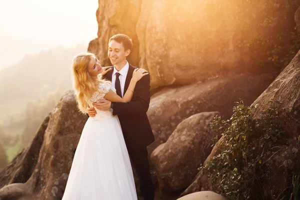 Pareja contra las rocas en las montañas al atardecer —  Fotos de Stock