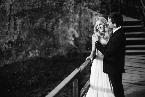 Gorgeous blond bride with her groom laughing near rocks enjoying each other