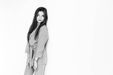 Anlamlı gözleri olan genç bayan beyaz duvara eğilir zerafet