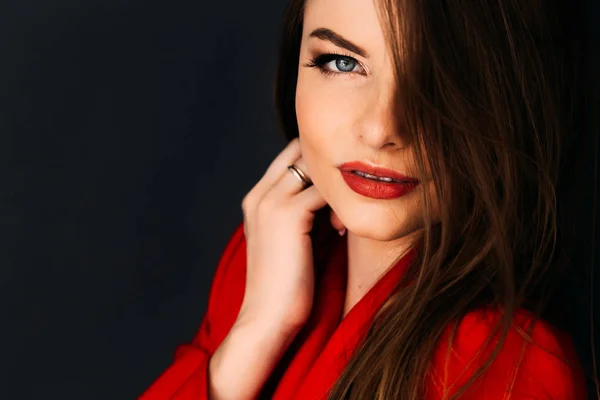 Koyu arka plan üzerinde kırmızı dudaklar ile kırmızı ceketli güzel model — Stok fotoğraf
