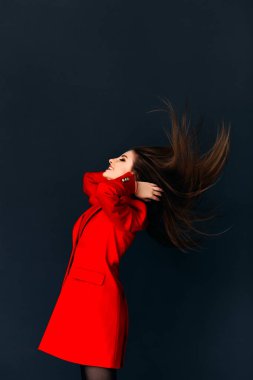 Kafasını sallayarak koyu arka plan üzerinde kırmızı palto giyiyor modeli