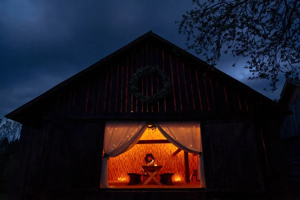 Wooden hut with table set inside lit by candles creating cozy at