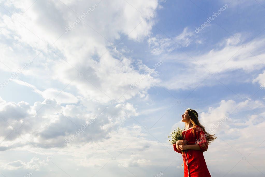Pretty girl in traditional ukrainian clothes looks into the sky 