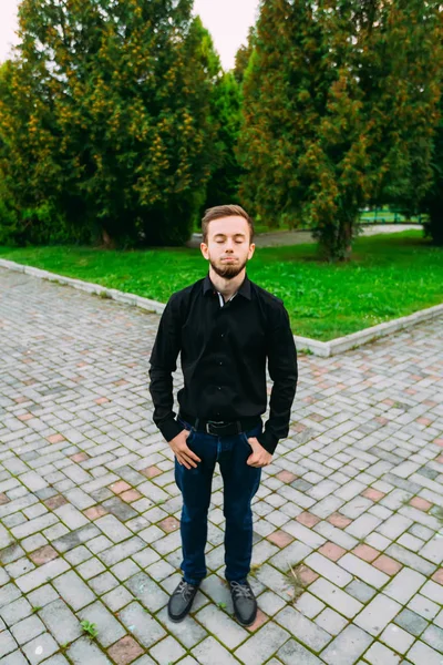 Elegante hombre cansado con los ojos cerrados de pie al aire libre — Foto de Stock