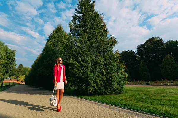 Gelukkig jonge vrouw op zomerdag. Mooi meisje in een roze jas een — Stockfoto