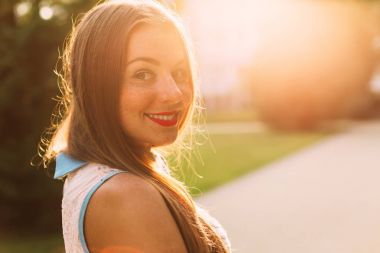 Gülen genç kadın uzun saçlı ve çilli bakarak geldi