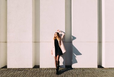 Uzun boylu manken ceket ve siyah elbise güneşli günde poz