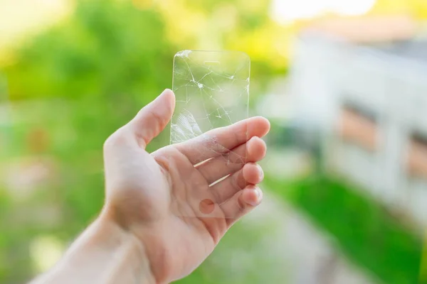 cracked screen protector for mobile in mans hand