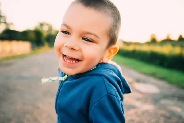 Портрет счастливого красавчика, смеющегося на улице. Маленький мальчик улыбается — стоковое фото