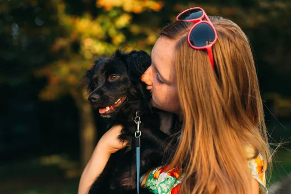 Little tender girl in a summer dress kissing her pet with love — Stock Photo, Image