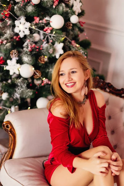 Sorridente giovane donna in abito rosso con decollete vicino a Natale d — Foto Stock