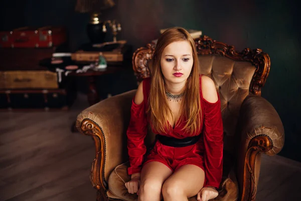 Triste jovem mulher em vestido vermelho sentado no interior de luxo — Fotografia de Stock