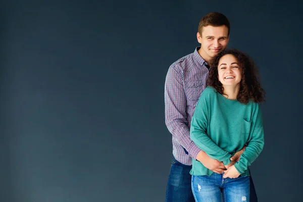 Jonge gelukkige paar knuffelen en lachen op blauwe achtergrond — Stockfoto