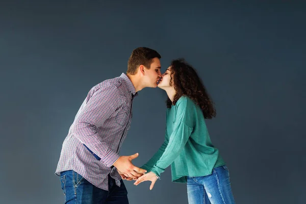 Молодой человек и женщина целуются и держатся за руки изолированные на голубом — стоковое фото