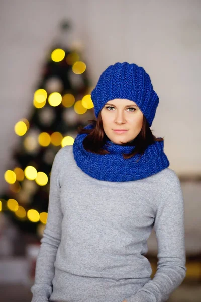 Woman in gray sweater and blue hat and knitted scarf against bok — Stock Photo, Image
