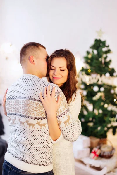 Imagen que muestra a una joven pareja abrazándose sobre un árbol de Navidad — Foto de Stock