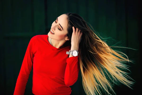 A beautiful girl in a red sweater holds her hand in her hair — Stock Photo, Image