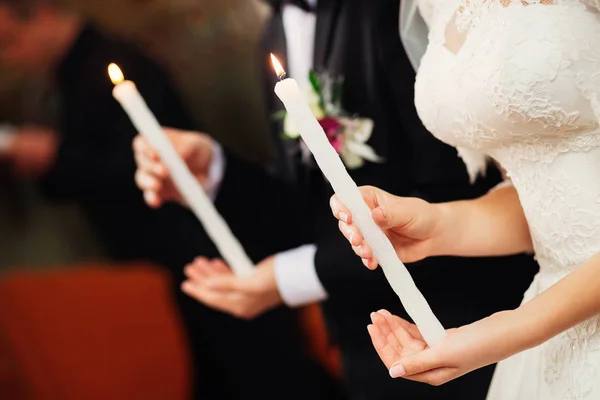 Les jeunes mariés tiennent des bougies sur leurs mains dans l'église — Photo