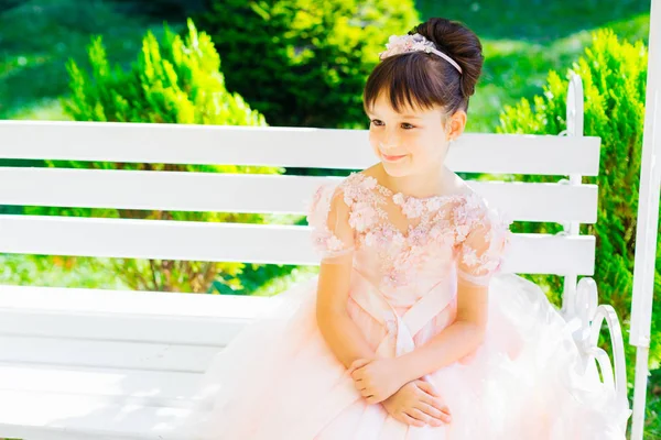 Mooi jong meisje in feestelijke kleding glimlachend zittend op wit — Stockfoto