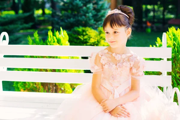 De mysterieuze blik van een jong meisje, zittend op een wit bankje — Stockfoto