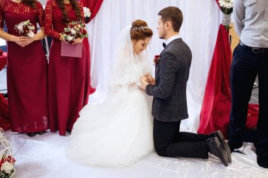 Gelin ve damat dizlerine el ele tutuşarak ayakta.