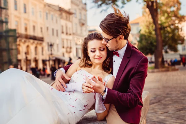 Una chica en un vestido de novia y un chico en una chaqueta relajarse en la ciudad —  Fotos de Stock