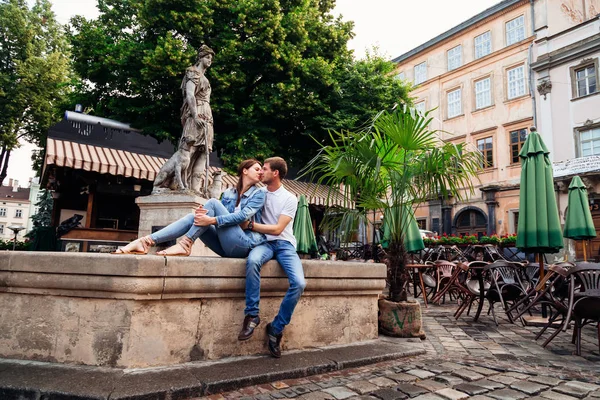 Bir erkek ve bir kadın oturma bir Çeşmede sarılma