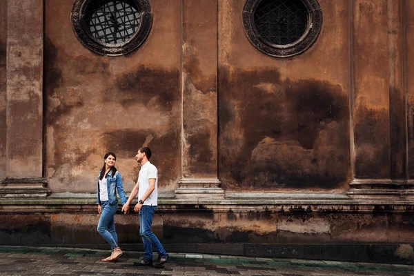 Un paseo de dos jóvenes que se toman de la mano cerca de un edificio viejo w — Foto de Stock