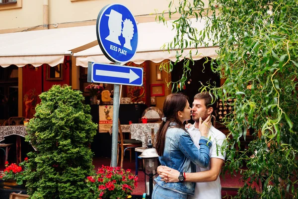 Namorada com namorado beijando sob o sinal "beijo lugar " — Fotografia de Stock