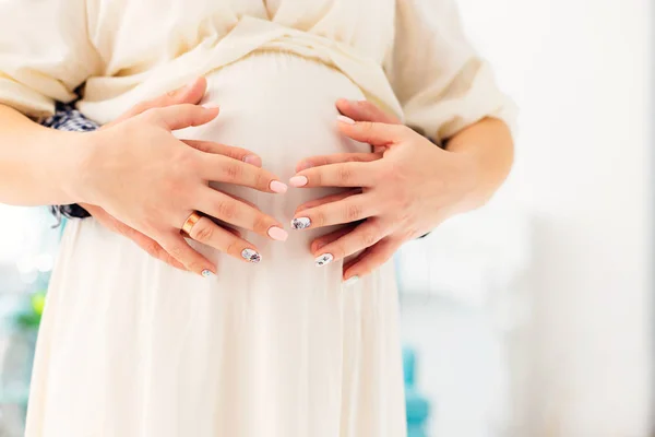 Een close-up van de buik van een zwangere vrouw. Handen van toekomstige par — Stockfoto
