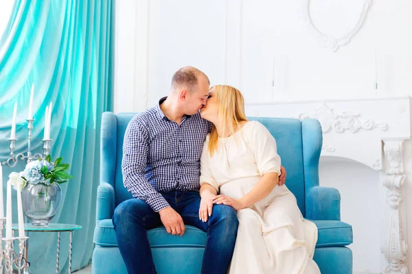 a kiss of two people sitting on the couch in a beautiful room and will soon become parents