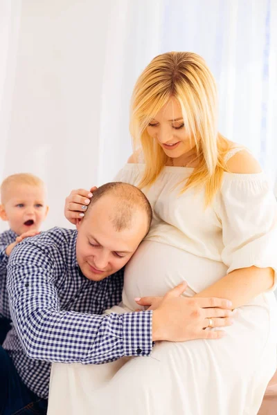 L'homme a mis son oreille sur le ventre de sa femme enceinte qui siège o — Photo