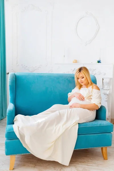 Kobieta Ciąży Siedząc Kanapie Luksusowe Trzymając Się Ręce Brzuchu Zza — Zdjęcie stockowe