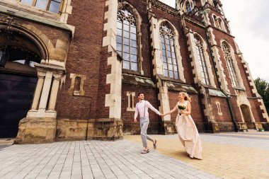 Güzel bir şık çocuk kız arkadaşının elini tutar ve onlar koşmak