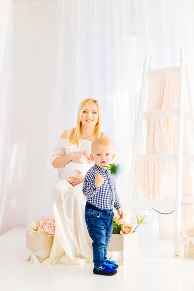 임신한 여자와 그 근처의 자에 앉아 하얀 드레스를 입고 — 스톡 사진