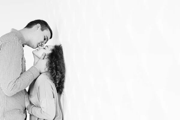 Sensual abrazo pareja cerca de una pared blanca en blanco y negro foto — Foto de Stock