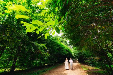 Festival kılığına girmiş bir çift yürüyüş boyunca yol üzerindeki yeşil arasında 