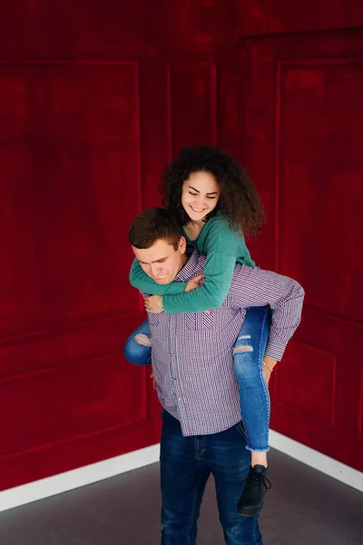 Een vriendin in stijlvolle kleding zit op de achterkant van haar boyfrien — Stockfoto