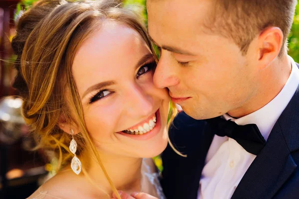 Upřímným úsměvem krásná nevěsta, při pohledu na fotoaparát zatímco ženich — Stock fotografie