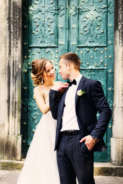 新郎看着他不可思议的新娘在美丽的蓝色门的背景 — 图库照片