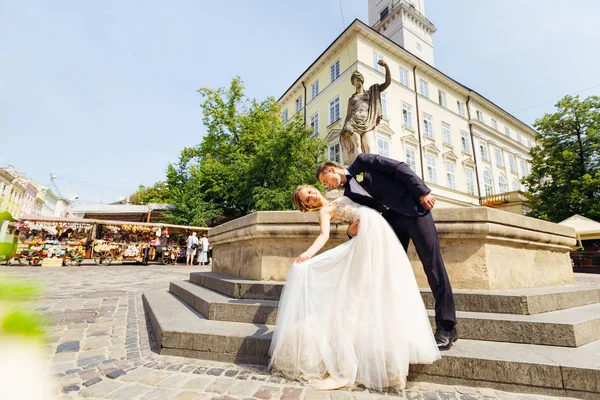 The bride has bent back near the statue in old European city and — стоковое фото