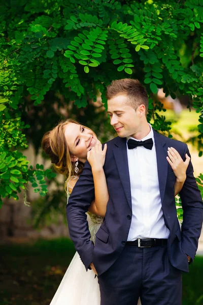 Heureuse mariée étreint son marié qui se tient dans un costume chic près d'un t — Photo