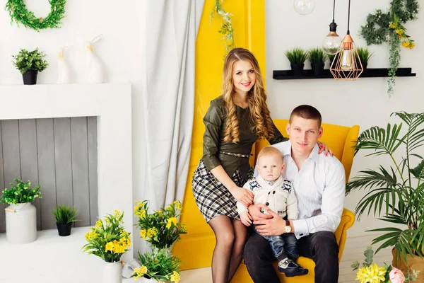 Felice famiglia seduta su una poltrona gialla chic e guardando in — Foto Stock