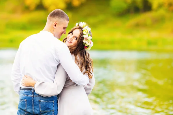 Het meisje haar vriendje achter de taille knuffels en blikt terug en — Stockfoto